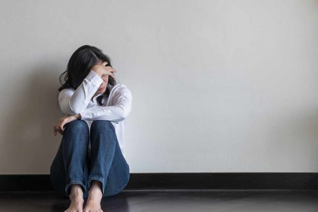 woman sitting on floor with knees to her chest suffering anxiety and depression