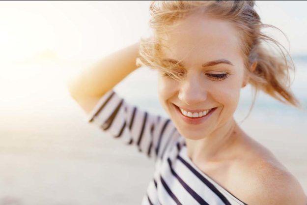 a woman smiling on a beach but wondering what is tms therapy